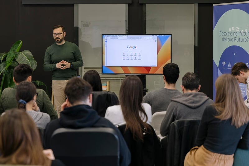 Una scena di webinar professionale con un gruppo eterogeneo di tre relatori (un uomo e due donne) seduti a un moderno tavolo da conferenza. L'uomo, con i capelli corti e scuri,